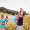 Family plays with children on the field with white flowers