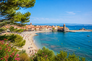 Vue panoramique d'une station balnéaire française en été avec plage, port et eaux turquoise.