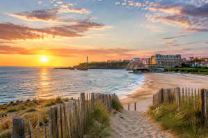 Station balnéaire française au coucher du soleil avec plage de sable, promenade et vue sur l'océan.