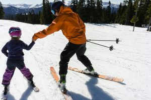 Une femme apprend à un enfant à skier